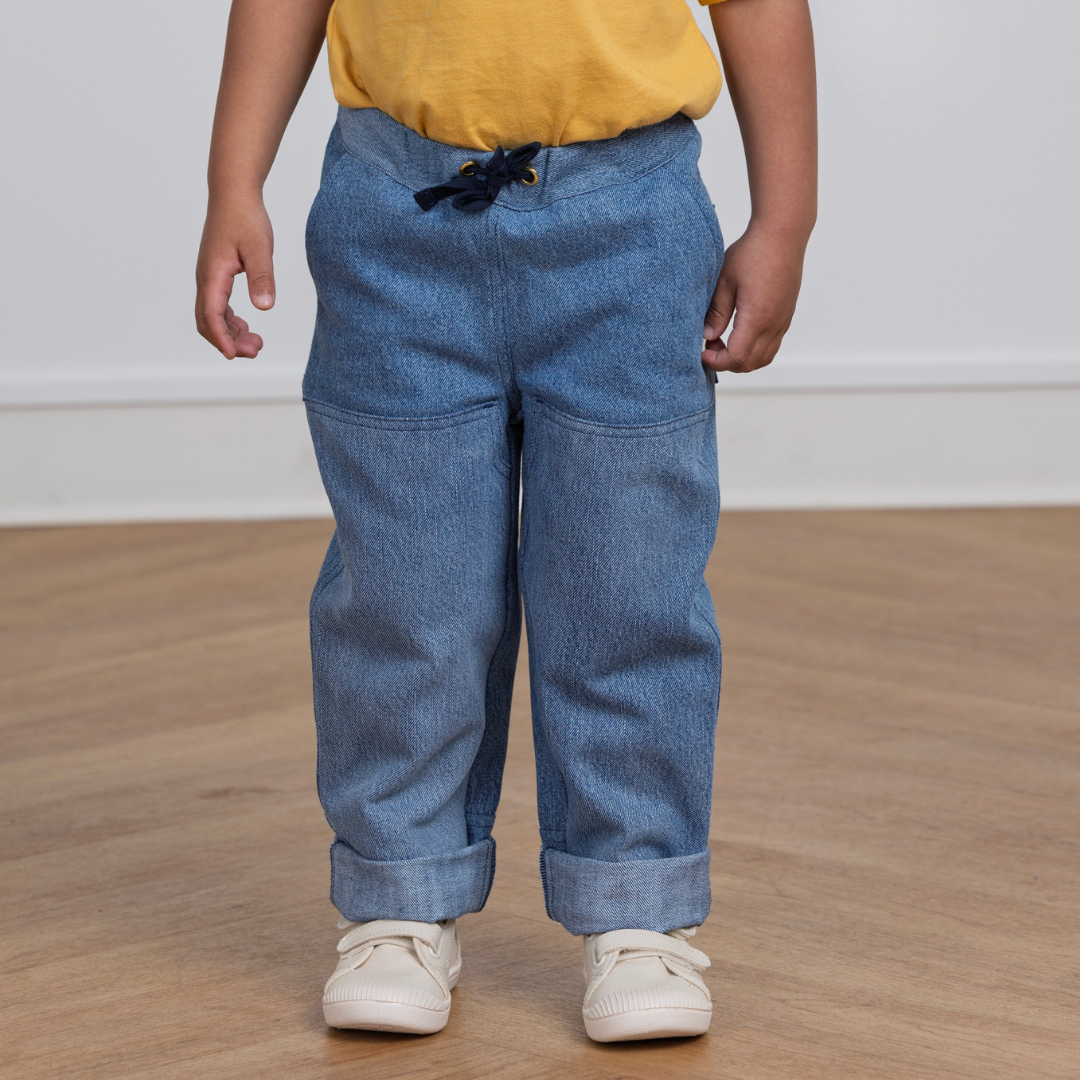 Kid wearing durable blue denim-style pants with drawstring waist, cuffed hems, and side pockets for active play