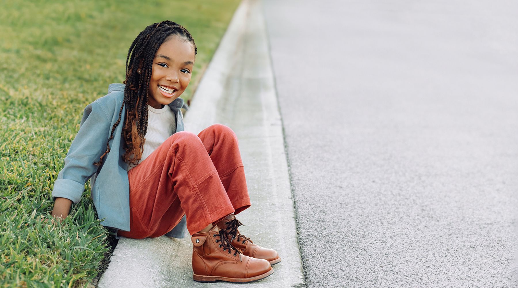 girl sitting on curb with jean jacket and red pants