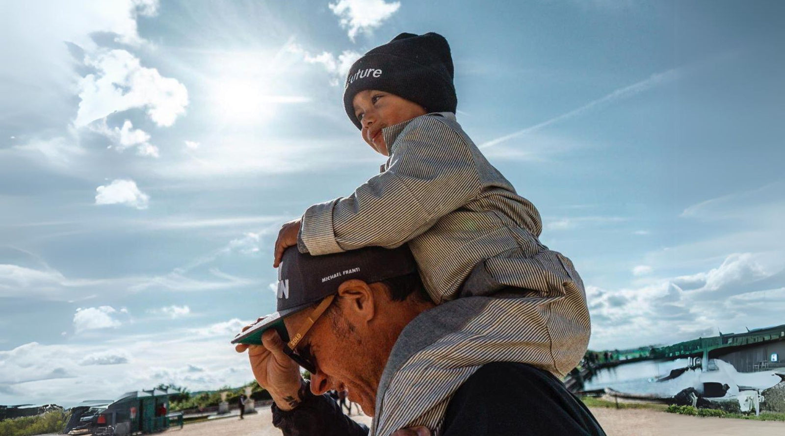 a man carrying a kid on his shoulders wearing a coveralls