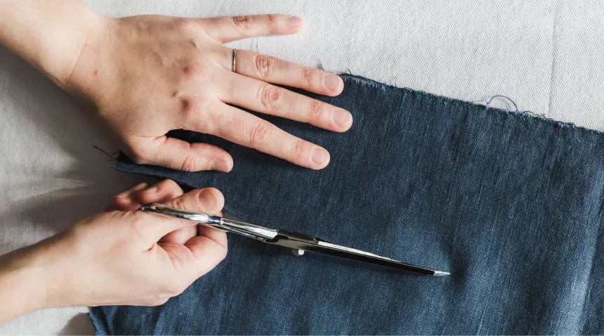 A person cutting fabric using a sharp scissors