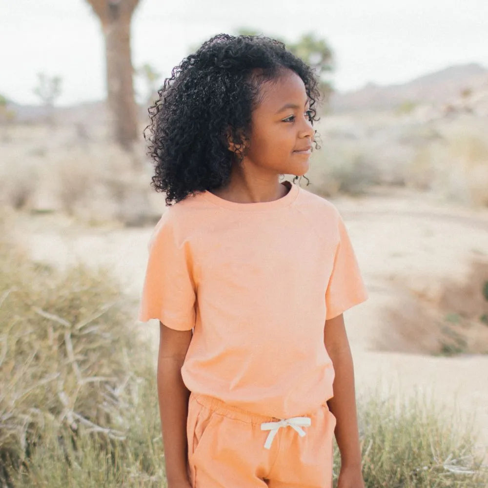 Girl in the desert wearing a peach shirt and shorts