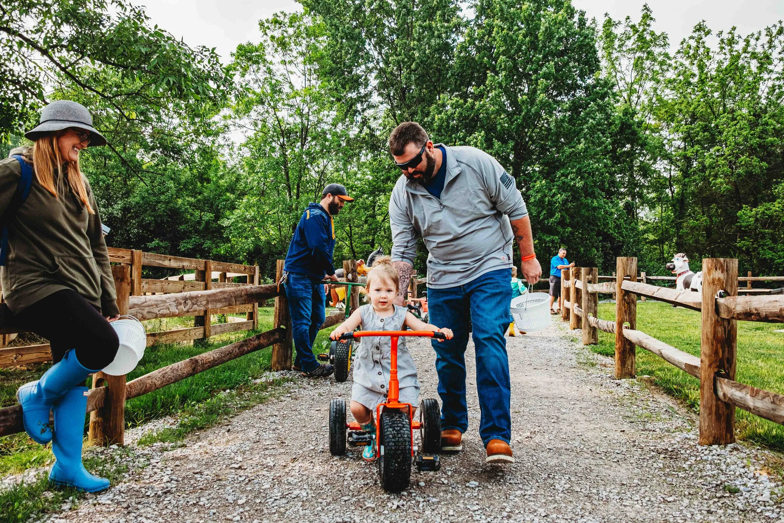 A man assisting a child riding a kid's tricycle