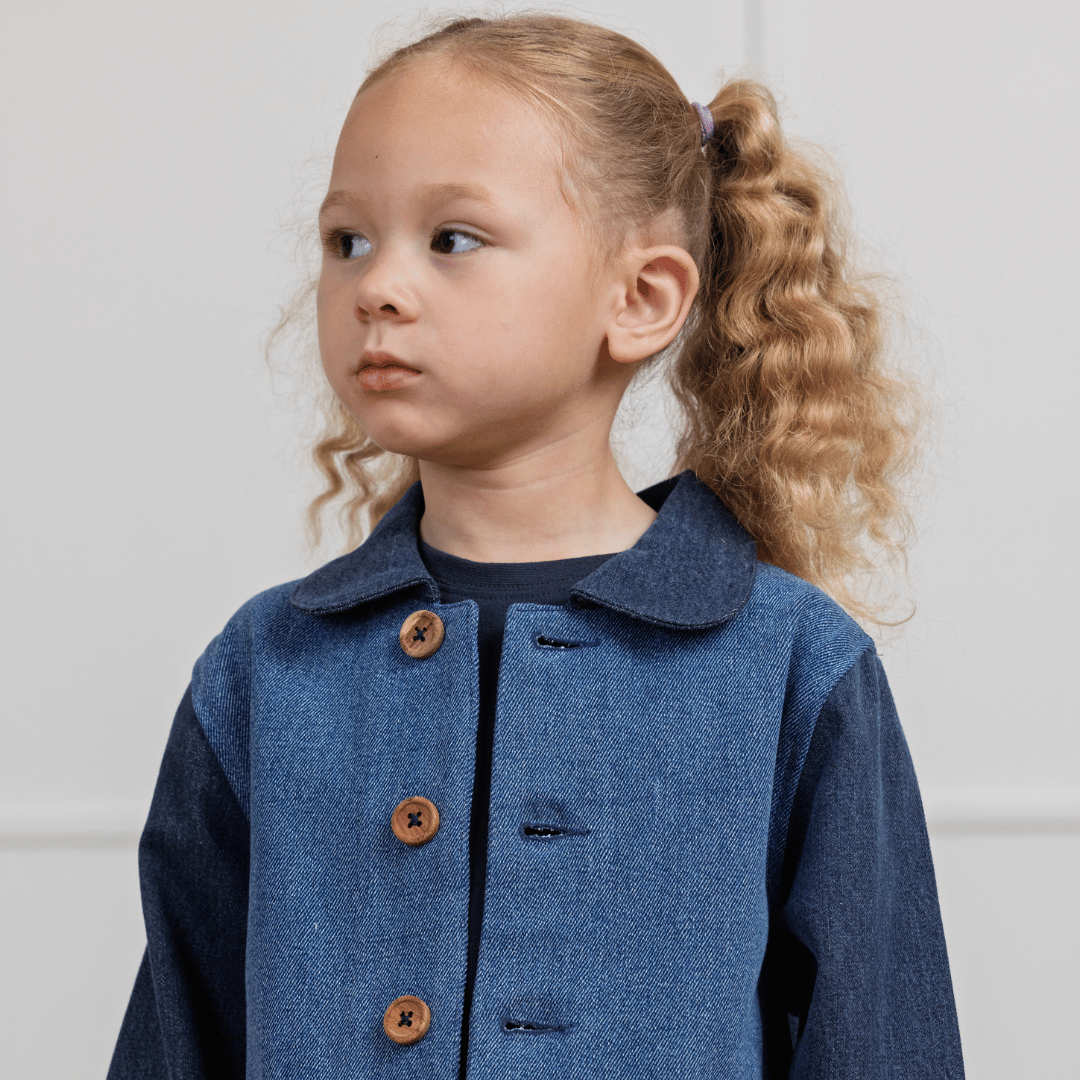 Toddler in durable denim jacket with wooden buttons, perfect for active kids' sustainable clothing