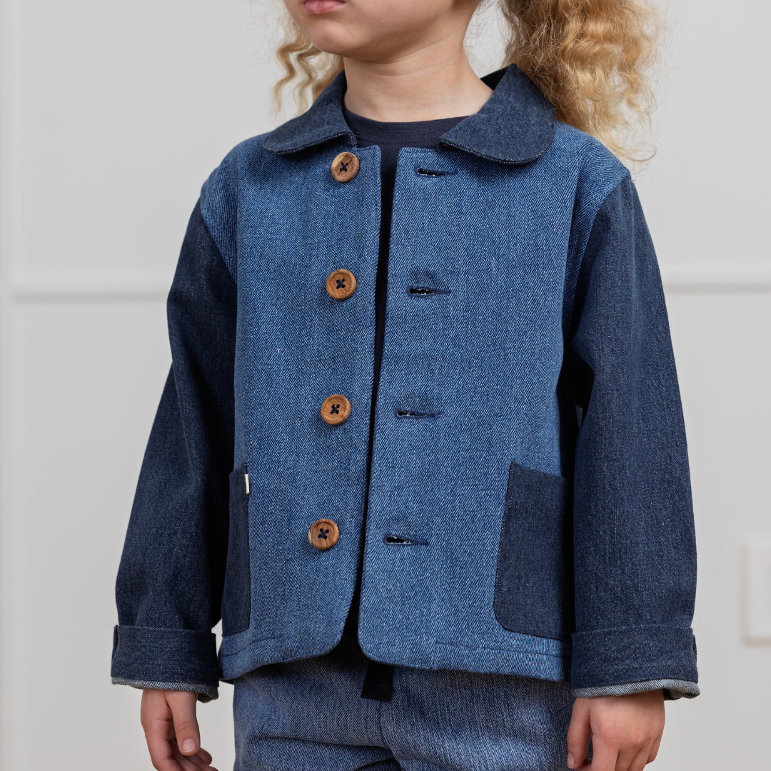Child wearing a blue coat with brown buttons against a white background