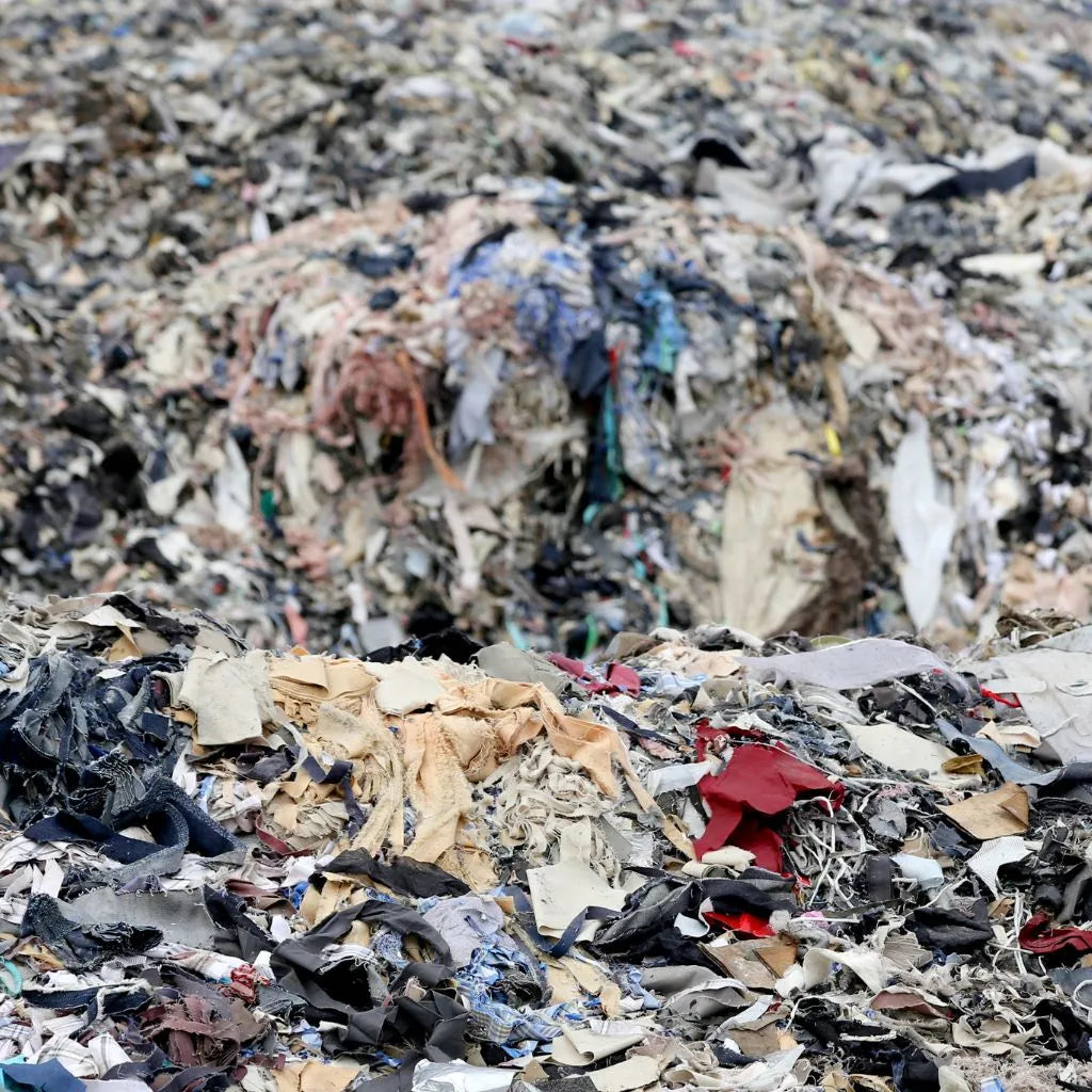 A pile of discarded dirty clothes rests in a landfill