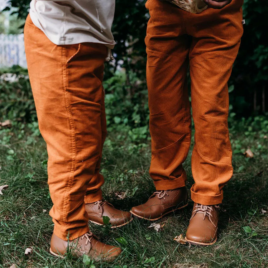 Cropped photo of kids wearing orange pants and brown leather shoes