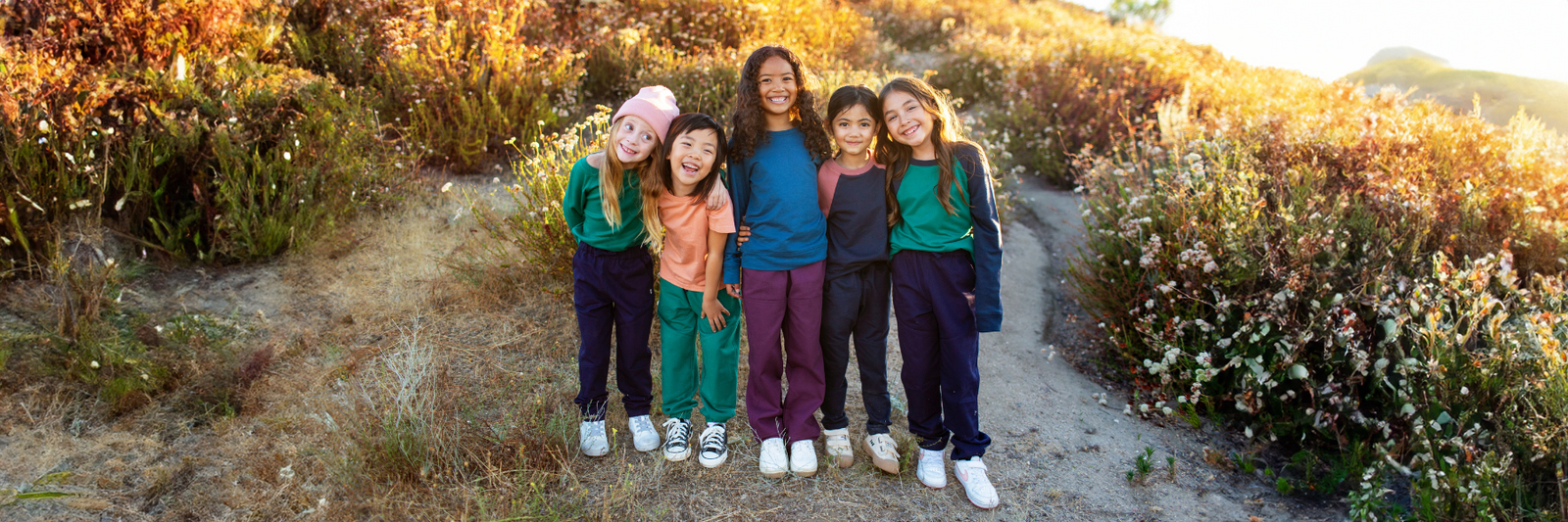 Four young girls joyfully standing on a grassy hill