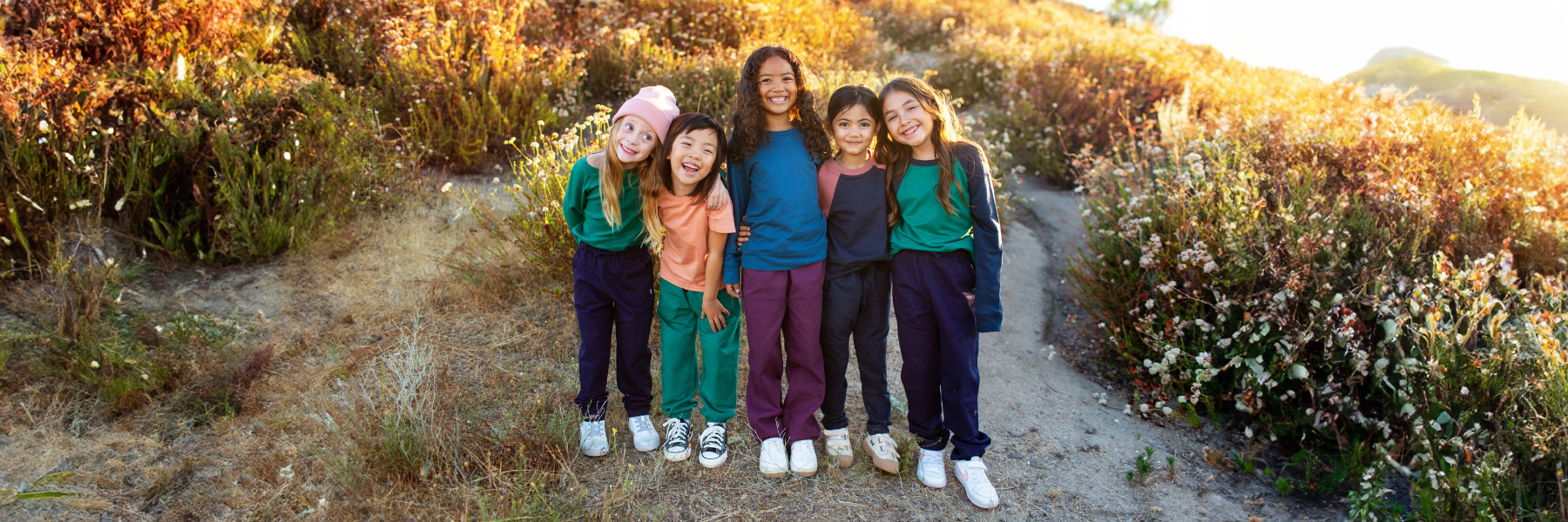 Four young girls joyfully standing on a grassy hill