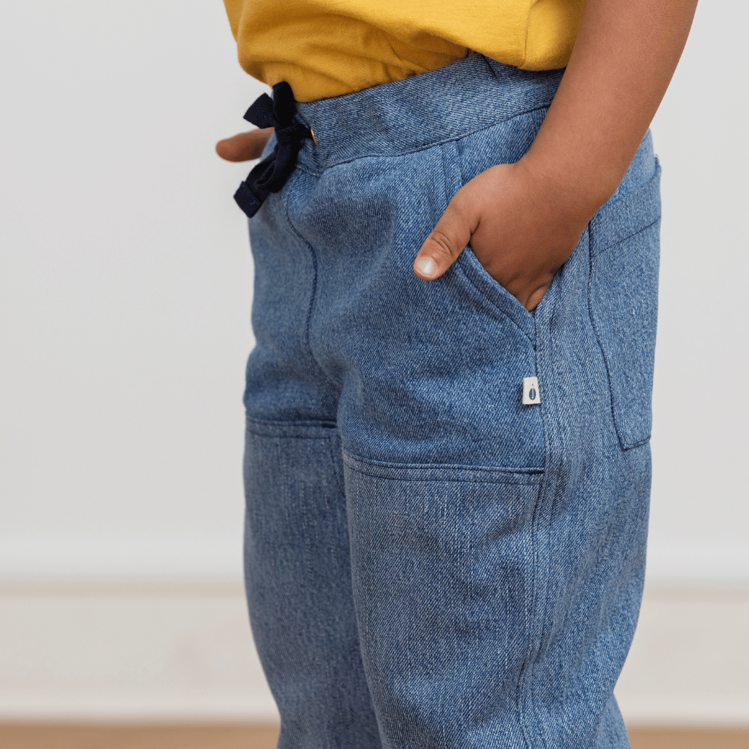 Child wearing blue denim-style joggers with drawstring waist and side pockets, paired with yellow top
