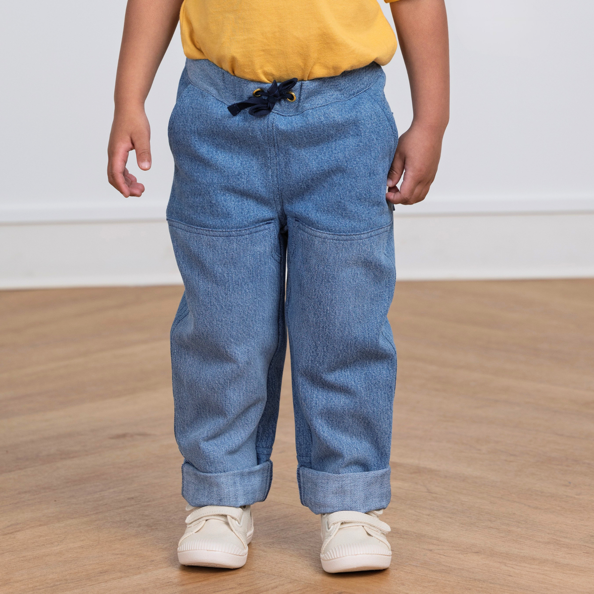 Kid wearing durable blue upcycled denim  pants with drawstring waist, cuffed hems, and side pockets for active play