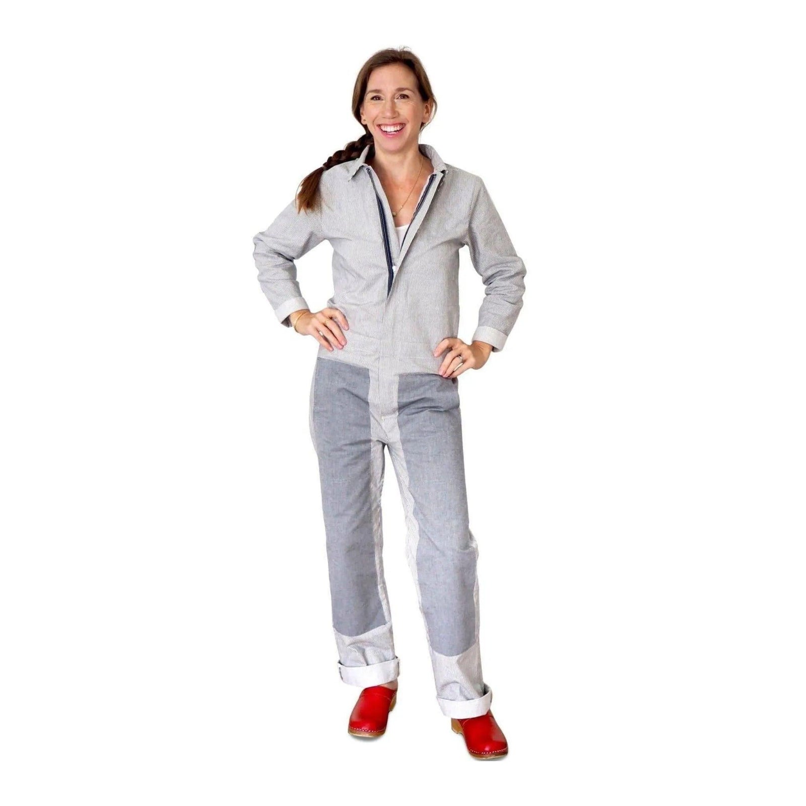 Woman wearing Jackalo sustainable chambray coverall with red clogs, hands on hips, white background.