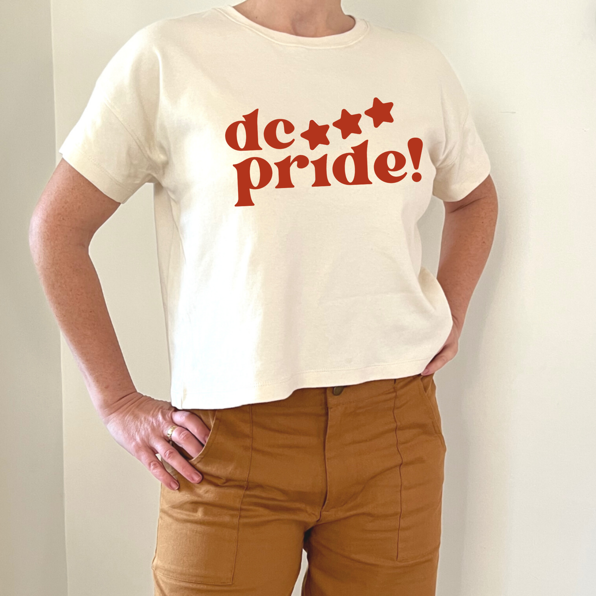 Cream crop tee with bold red 'dc pride!' graphic and stars, paired with mustard pants