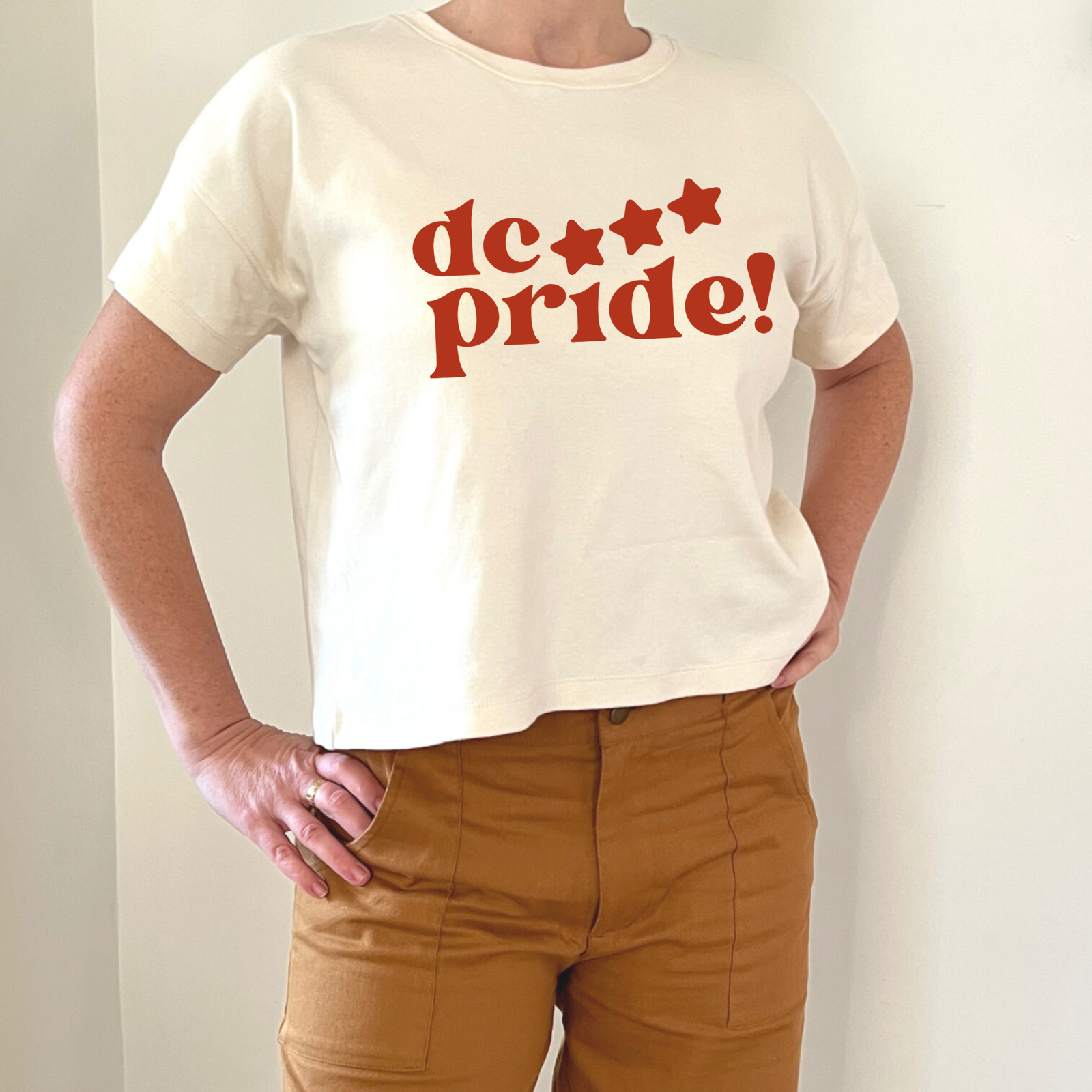 Cream crop tee with bold red 'dc pride!' graphic and stars, paired with mustard pants