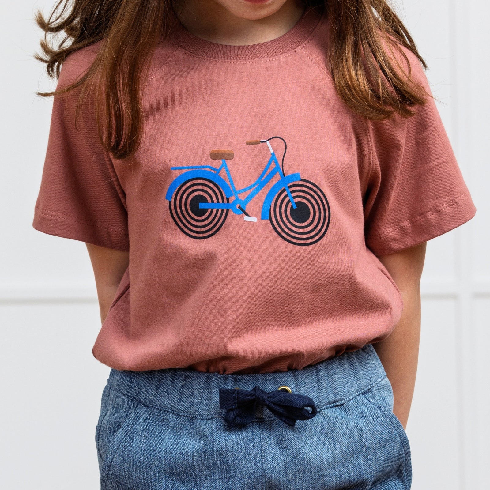 Girl in Rose t-shirt with Bike print on it. Organic cotton t-shirt from Jackalo.