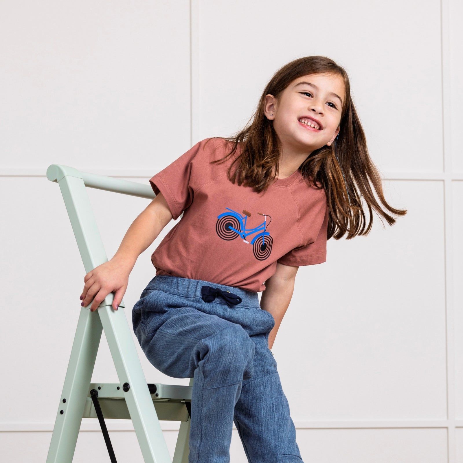 Girl in Rose t-shirt with Bike print on it. Organic cotton t-shirt from Jackalo.