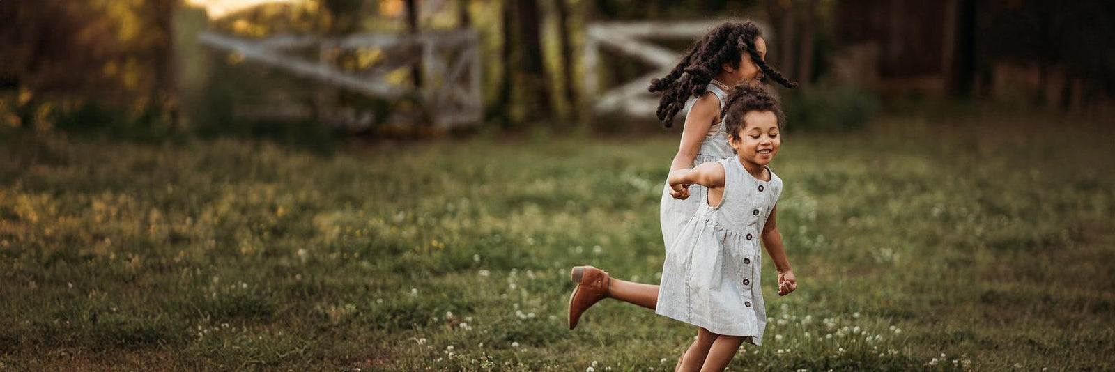 Two sisters holding hands while running through the yard