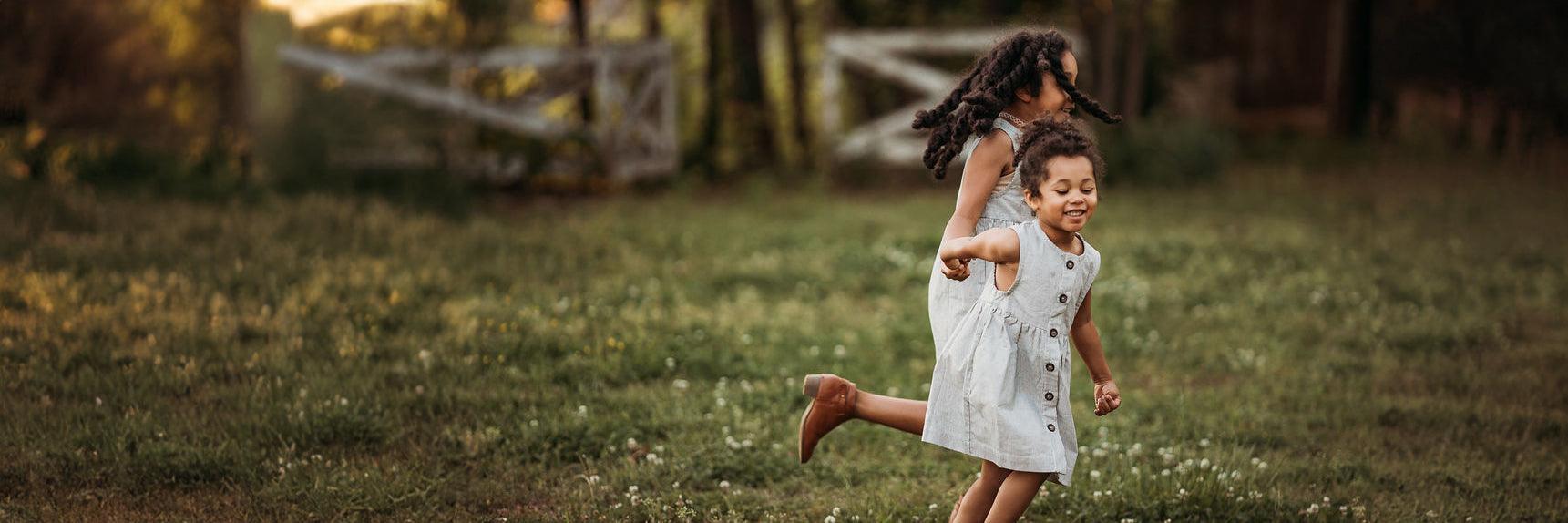 Two sisters holding hands while running through the yard