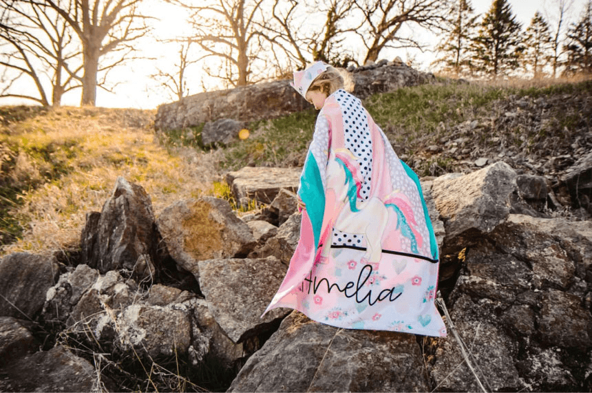 A girl standing on a rock with a blanket