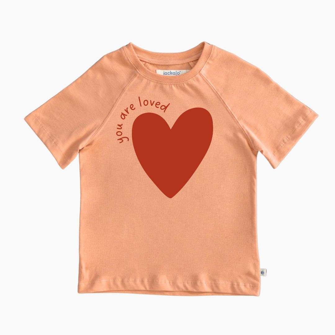 Organic peach-colored t-shirt with a red heart and 'you are loved' text on a white background