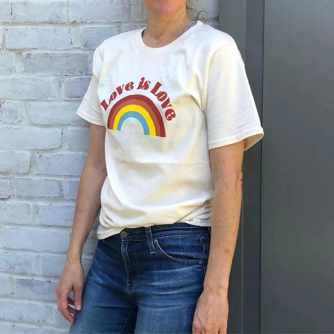 Adult wearing white shirt with &quot;Love is Love&quot; design