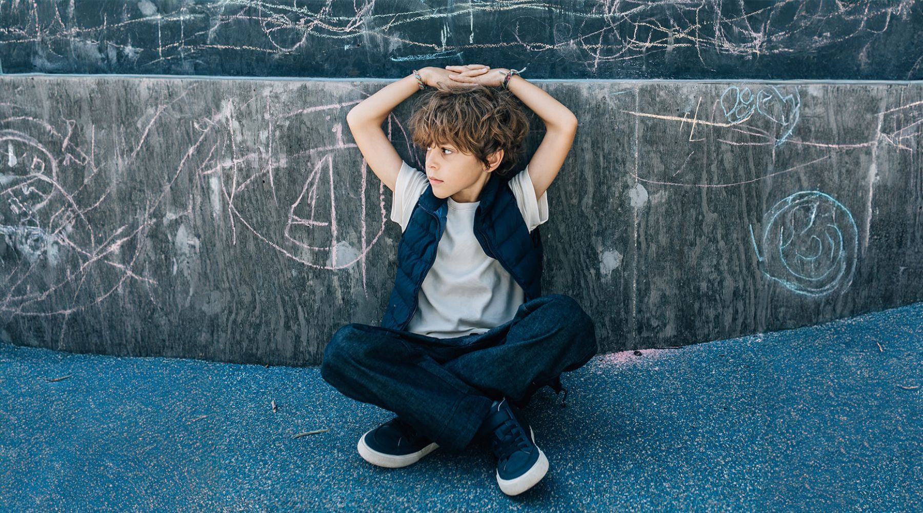 boy sitting against grafiti wall