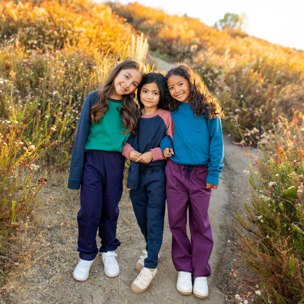 Three girls in purple and blue outfits standing together