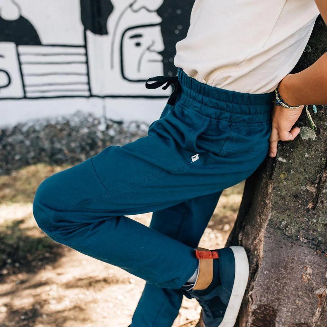 Cropped photo of a kid wearing white shirt and dark blue sweatpants