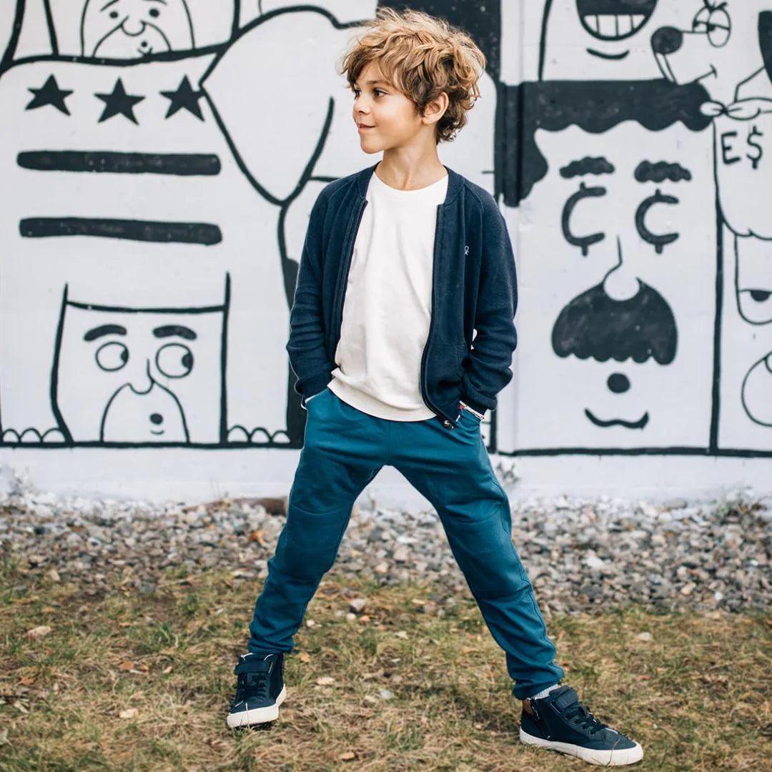 Cropped photo of a kid wearing white shirt and dark blue sweatpants