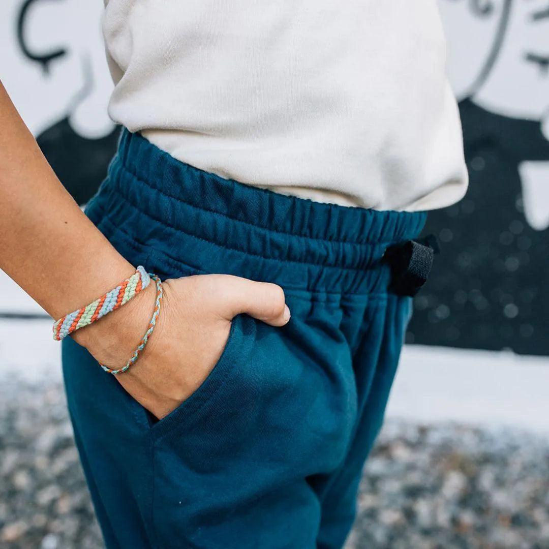 Cropped photo of a kid wearing white shirt and dark blue sweatpants