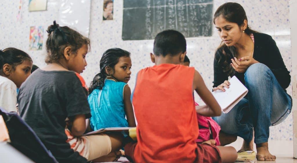 A teacher engaging with children in a bright classroom