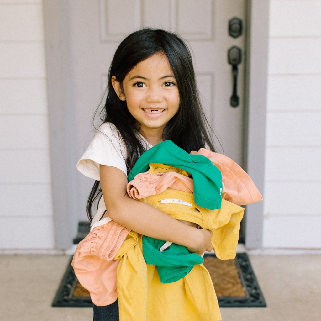 young girl standing holding her clothes